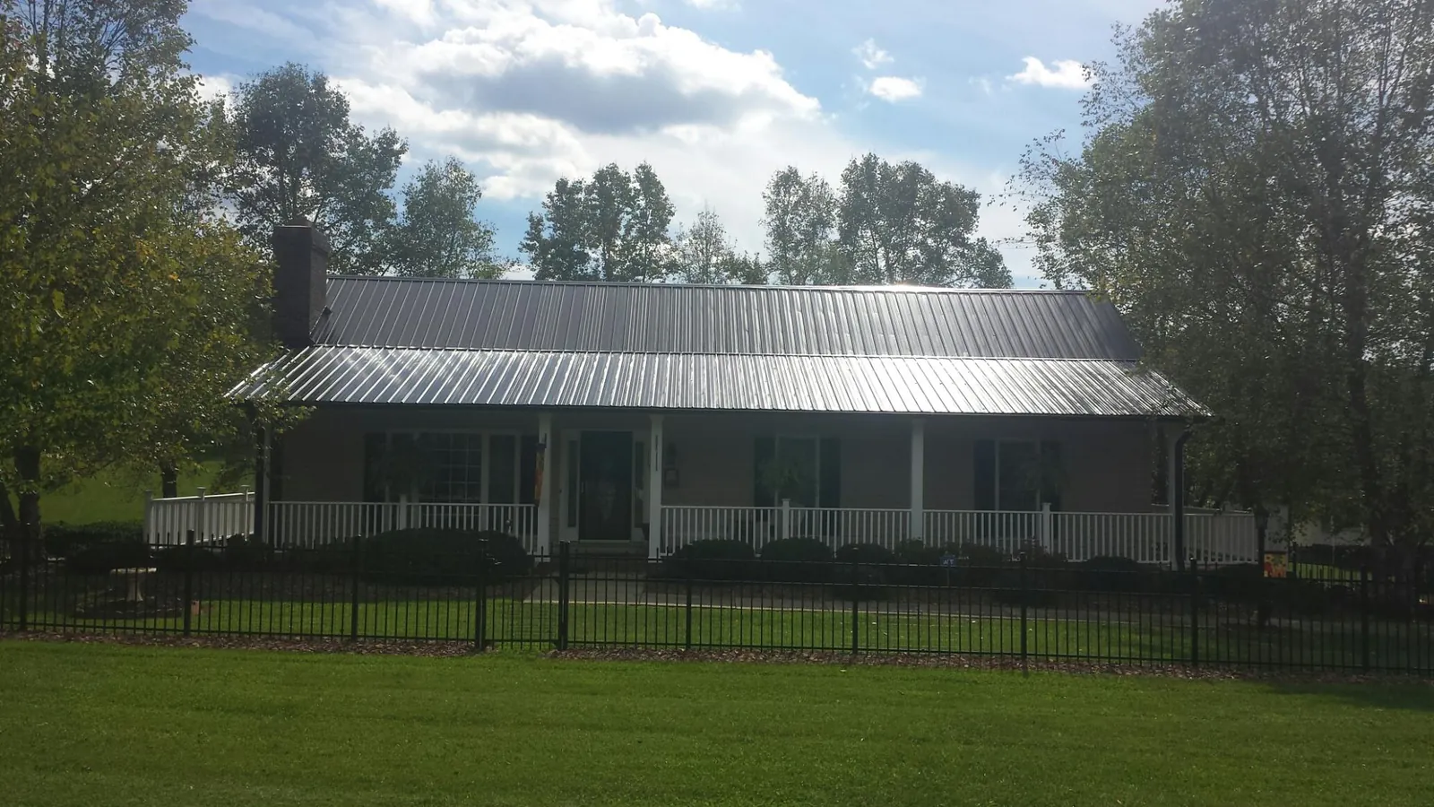 Gray metal roof on a brick ranch with a full width front porch — Gutter Guard Installation work by our crew in Spring Valley