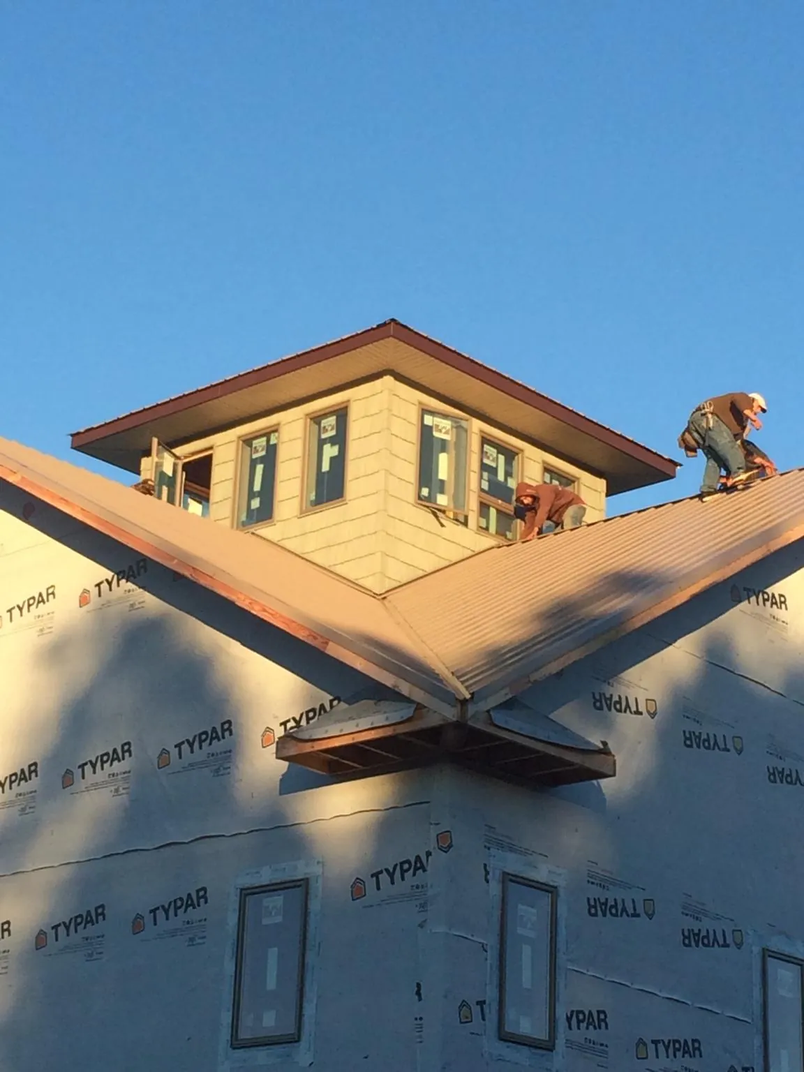 Roofers working around a rooftop cupola on a new metal roof at sunset — Roof Waterproofing in Spring Valley by Roofing Brothers